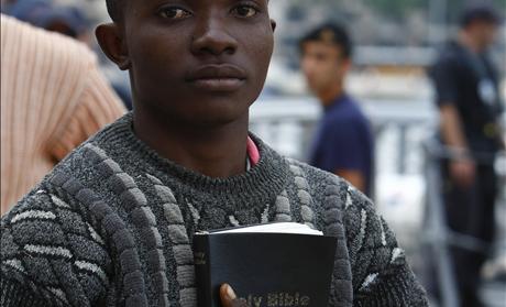 African immigrant carrying a bible disembarks from an Armed Forces of Malta patrol boat after arriving in Valletta's Marsamxett Harbour