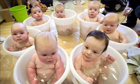 Seven babies sit in tummy tubs filled with water to cool down after a baby massage class held for young mothers in IJmuiden