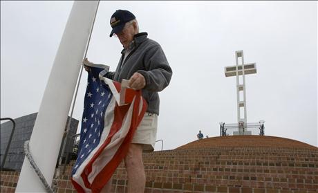 Clyde Rights raises flag next to Mount Soledad Cross which is being transferred to federal government ownership