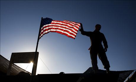 A U.S. Marine from 3rd Battalion 4th Marines, adjusts the U.S. flag on the top of his tent on base Delaram in Nimroz province