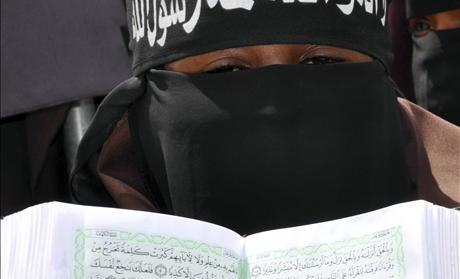 A pro Al-Shabaab female demonstrator holds a copy of the Koran during a protest against the burning of the Islamic holy book in Mogadishu