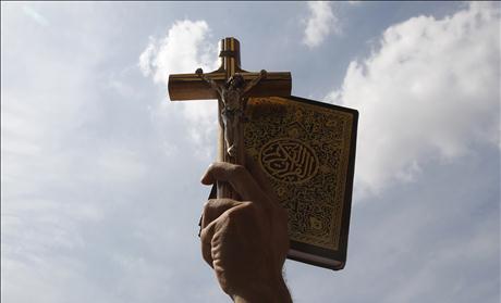 An Egyptian holds up a Koran and a cross during a rally to demonstrate the unity between Muslims and Christians at Tahrir Square in Cairo
