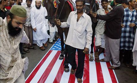 Indian Muslims shout anti-US slogans as they ride horses over the U.S. flag during a demonstration