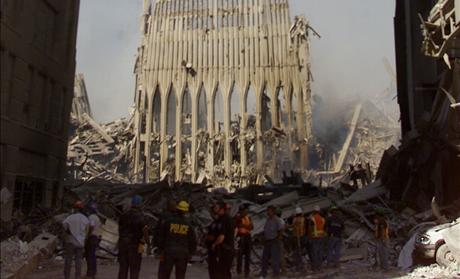 RESCUE WORKERS STAND NEXT TO WALL OF WORLD TRADE CENTER.