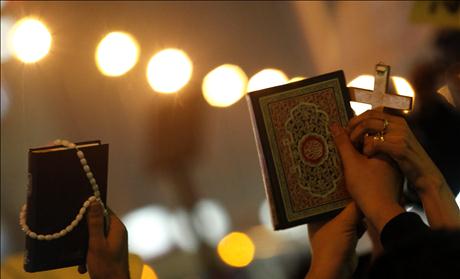 Egyptian Muslims and Christians hold a Koran and a cross in the Shobra district of Cairo