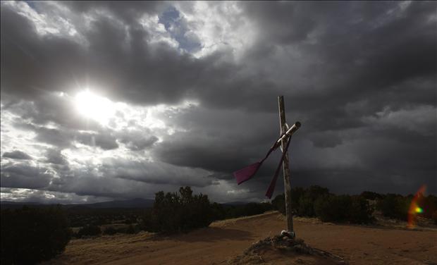 A cross is seen on the hill as the sun rises on Easter morning in Chimayo 