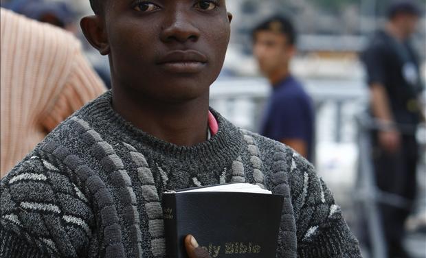 African immigrant carrying a bible disembarks from an Armed Forces of Malta patrol boat after arriving in Valletta's Marsamxett Harbour 