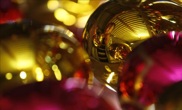 A woman painting a Christmas ornament is reflected on a bauble at a workshop in the village of Chignahuapan in Puebla