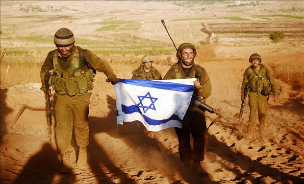 Israeli soldiers hold Israeli flag after leaving Lebanon near Israeli-Lebanon border