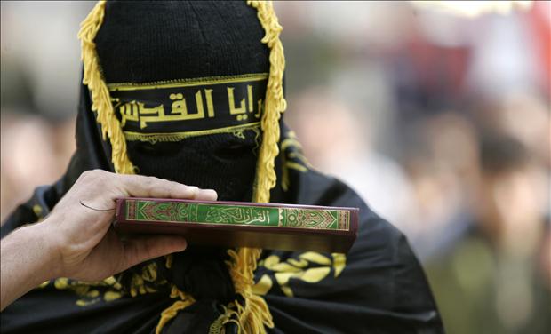 Palestinian militant from Islamic Jihad kisses copy of Koran in West Bank village of Qabateanear