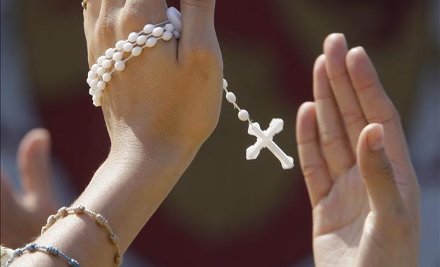 A woman, holding her rosary, claps her hands in time with music during a youth rally for Pope Benedict XVI in Yonkers New York