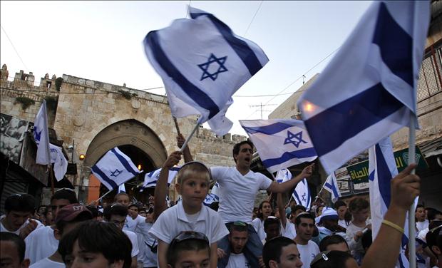 Israelis wave national flags during a parade marking Jerusalem Day in front of the Damascus Gate in Jerusalem's Old City