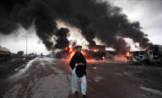 A fire fighter gestures in front of burning oil tankers which were attacked by unidentified gunmen on the outskirts of Peshawar