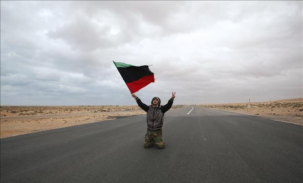 An anti-Gaddafi rebel prays and chants along a road during clashes with pro-Qaddafi forces near Ras Lanuf