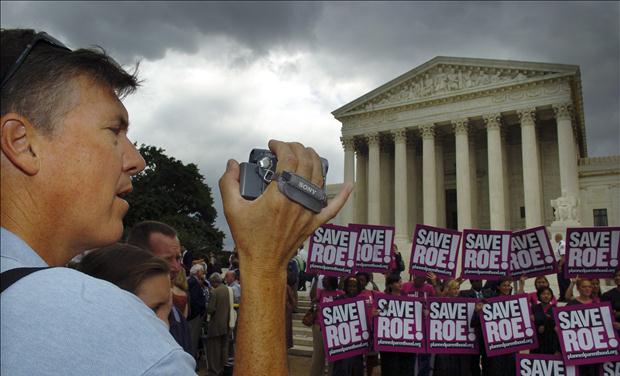 A tourist makes home movies of the crowd gathered at the US Supreme Court in Washington.