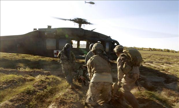 A Blackhawk helicopter from CCO., 1-214 AVN flies overhead as U.S. Marines and members of the Afghan Army carry a wounded Afghan soldier to a helicopter during a Medevac mission in southern Afghanistan's Helmand province