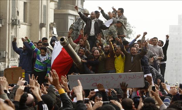 Demonstrators celebrate atop an army tank in Tahrir square during protests in Cairo