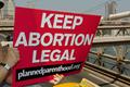 Planned Parenthood abortion rights protester signals Brooklyn Bridge traffic.