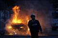 Israeli police officer stands in front of burning car in Ashkelon