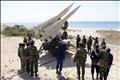 Members of Iran's army stand around the Hug missile as they take part in a war game in Jask port
