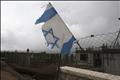 An Israeli national flag is seen as Palestinian labourers work on a building under construction in the Jewish settlement of Har Gilo