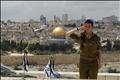 An Israeli soldier salutes after placing flags on the graves of fallen soldiers at the military cemetery on the Mount of Olives in Jerusalem