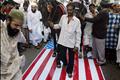 Indian Muslims shout anti-US slogans as they ride horses over the U.S. flag during a demonstration