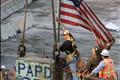 A worker holds up an American flag after cutting it from atop the last support beam from the south tower